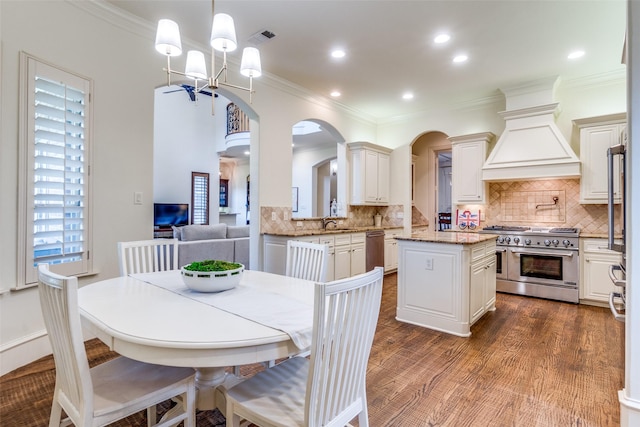 dining area with arched walkways, ornamental molding, plenty of natural light, a chandelier, and dark wood finished floors