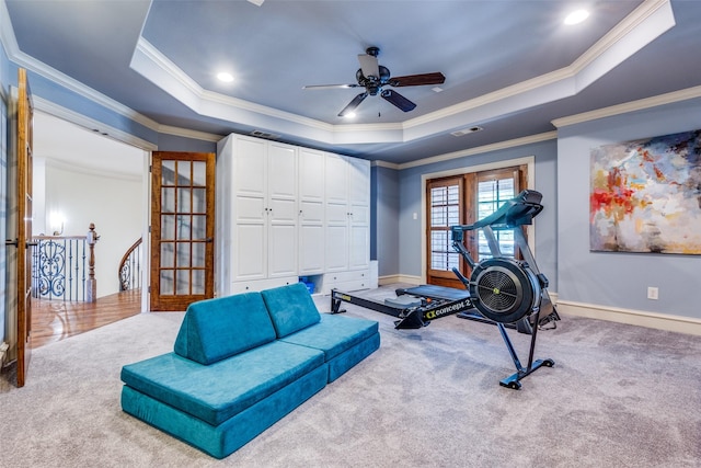 workout area featuring carpet flooring, ornamental molding, a raised ceiling, a ceiling fan, and baseboards