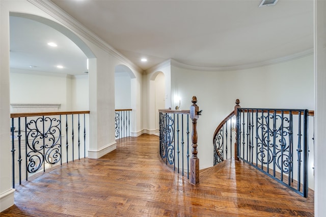 hallway with wood finished floors, arched walkways, an upstairs landing, recessed lighting, and ornamental molding