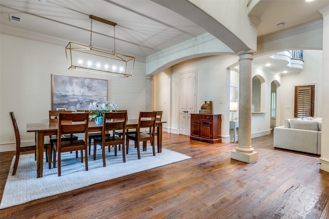 dining area featuring crown molding, wood finished floors, baseboards, and arched walkways