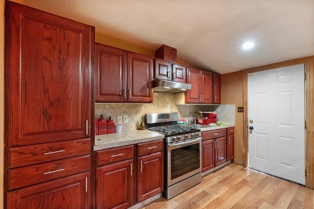 1017 S Newark Ave, Fort Worth, TX 76105 - kitchen with stainless steel range with gas cooktop, under cabinet range hood, light wood-style floors, light countertops, and tasteful backsplash