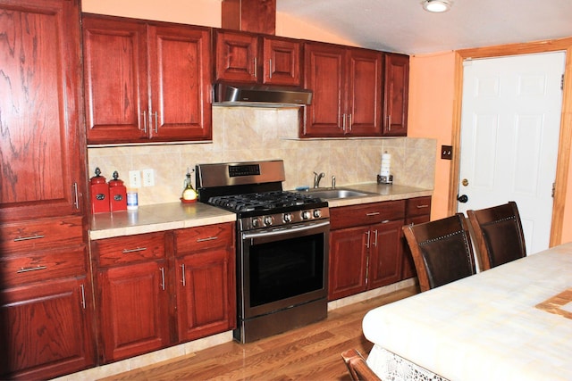 1017 S Newark Ave, Fort Worth, TX 76105 - kitchen with stainless steel gas stove, exhaust hood, a sink, light countertops, and reddish brown cabinets