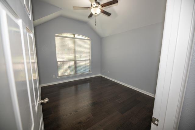 107 Harvest Way, Crandall, TX 75114 - spare room with a ceiling fan, dark wood-style floors, vaulted ceiling, and baseboards
