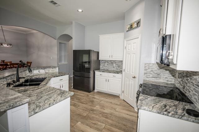 107 Harvest Way, Crandall, TX 75114 - kitchen with freestanding refrigerator, a sink, arched walkways, light wood-type flooring, and white cabinets