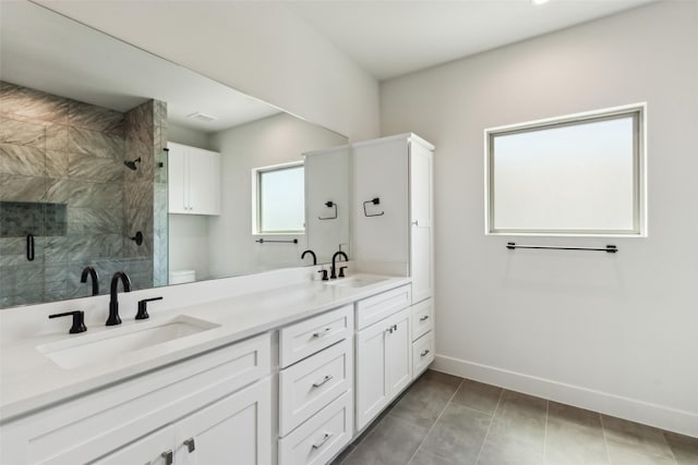 13900 Noel Rd Unit 401, Dallas, TX 75240 - bathroom featuring a stall shower, baseboards, double vanity, toilet, and tile patterned flooring
