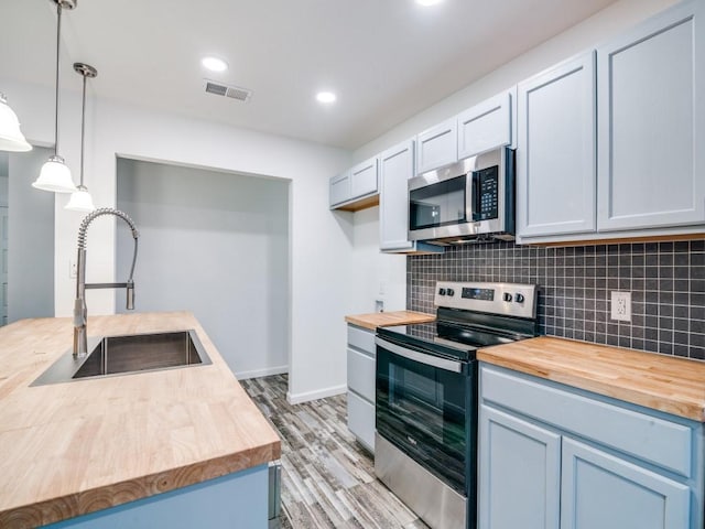3906 Westview Dr, Rowlett, TX 75088 - kitchen featuring wooden counters, appliances with stainless steel finishes, a sink, light wood-type flooring, and recessed lighting
