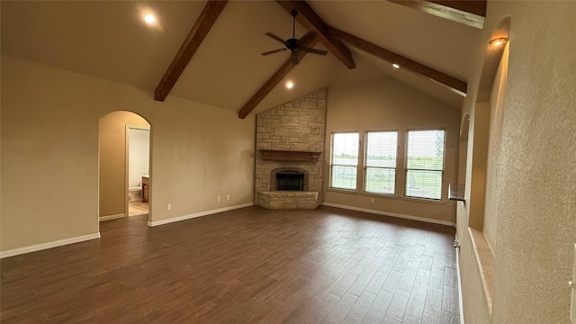 124 Heritage Pkwy W, Decatur, TX 76234 - unfurnished living room featuring beam ceiling, ceiling fan, arched walkways, dark wood-type flooring, and a fireplace