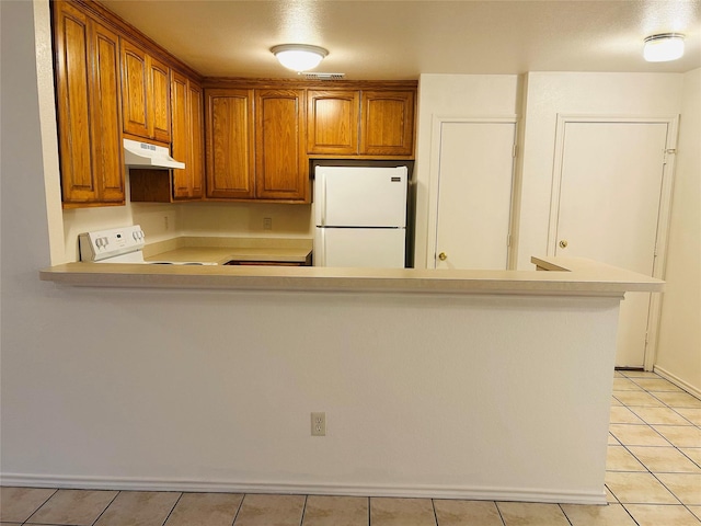 601 Lawrence Ave, Terrell, TX 75160 - kitchen with freestanding refrigerator, under cabinet range hood, light countertops, brown cabinetry, and light tile patterned floors