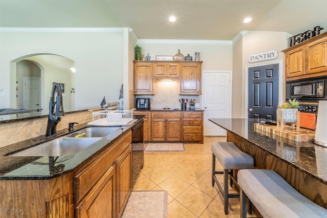 2113 Old Foundry Rd, Weatherford, TX 76087 - kitchen featuring a sink, black appliances, decorative backsplash, ornamental molding, and a breakfast bar
