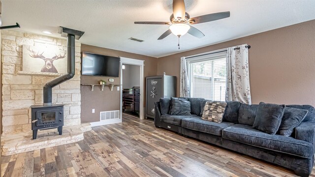 8147 Fawn Cir, Granbury, TX 76049 - living area with a wood stove, ceiling fan, wood finished floors, baseboards, and a textured ceiling