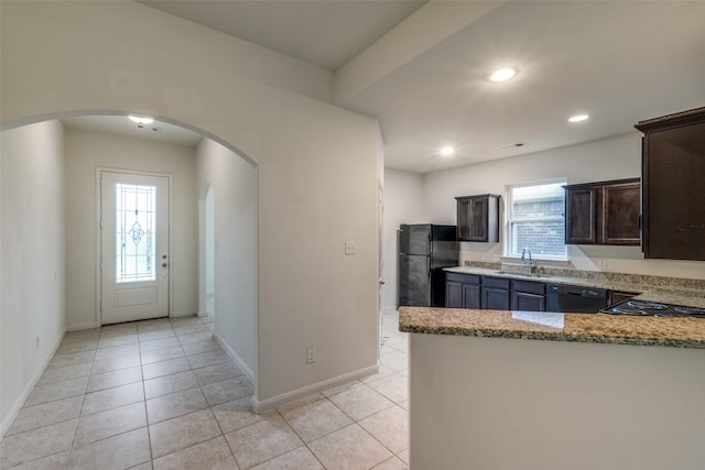 4601 Shy Creek Ln, Denton, TX 76207 - kitchen with black appliances, arched walkways, light stone countertops, dark brown cabinets, and light tile patterned floors