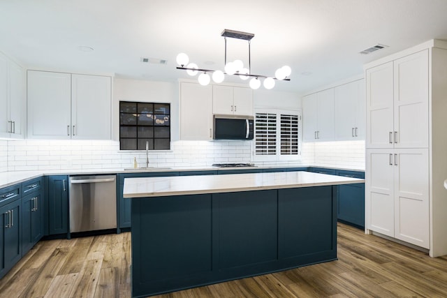 kitchen featuring appliances with stainless steel finishes, a sink, blue cabinets, and white cabinetry