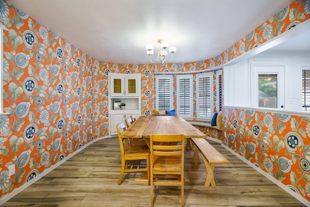 dining room featuring wallpapered walls, a chandelier, baseboards, and wood finished floors