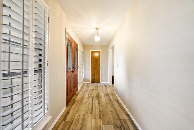 hall featuring light wood-type flooring, french doors, and baseboards