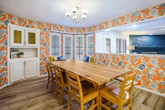 dining room with wallpapered walls, wood finished floors, a chandelier, and baseboards