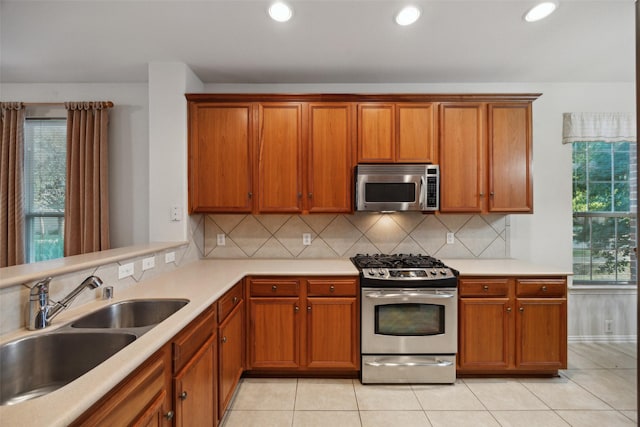 7552 Angel Trace Dr, Frisco, TX 75036 - kitchen featuring appliances with stainless steel finishes, a sink, backsplash, brown cabinets, and light countertops