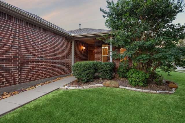 7552 Angel Trace Dr, Frisco, TX 75036 - view of exterior entry with brick siding, a yard, and a shingled roof