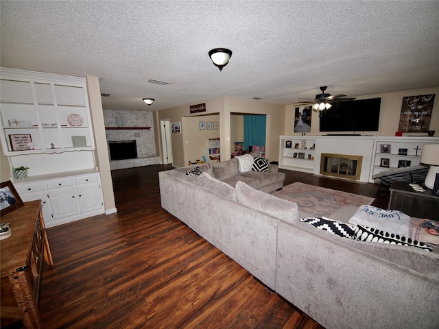 804 Austin Rd, Graham, TX 76450 - living area with a fireplace, dark wood-style floors, a ceiling fan, and a textured ceiling