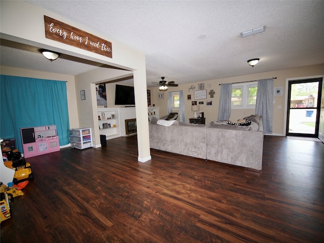 804 Austin Rd, Graham, TX 76450 - living room featuring dark wood-type flooring, a textured ceiling, ceiling fan, a glass covered fireplace, and baseboards