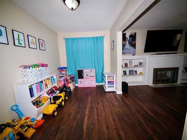 804 Austin Rd, Graham, TX 76450 - playroom featuring wood finished floors, a textured ceiling, a brick fireplace, and baseboards