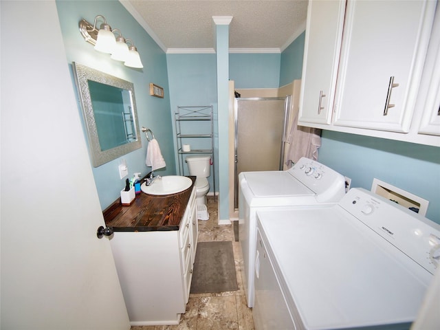 804 Austin Rd, Graham, TX 76450 - washroom featuring washing machine and clothes dryer, ornamental molding, a textured ceiling, and cabinet space