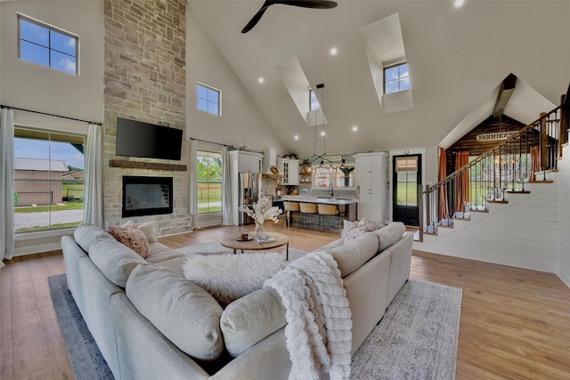 1299 Harmony Cir, Weatherford, TX 76087 - living room featuring high vaulted ceiling, stairs, light wood finished floors, a skylight, and a ceiling fan
