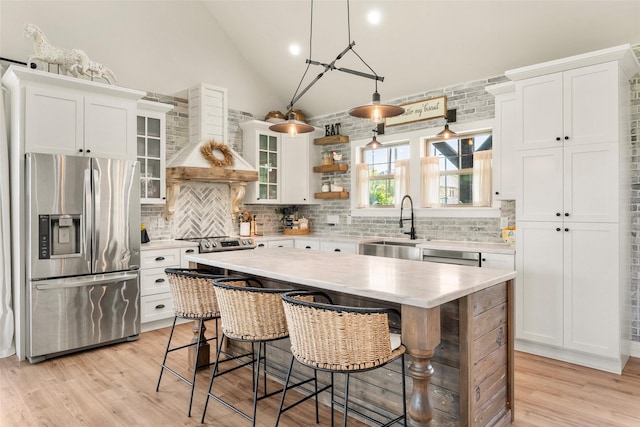 1299 Harmony Cir, Weatherford, TX 76087 - kitchen with stainless steel fridge with ice dispenser, wall chimney exhaust hood, light countertops, vaulted ceiling, and white cabinets