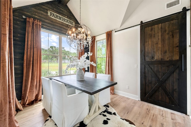 1299 Harmony Cir, Weatherford, TX 76087 - dining space with a barn door, a chandelier, vaulted ceiling, light wood finished floors, and baseboards
