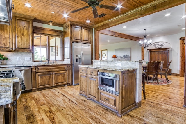 1633 Scenic Dr Unit 201, Graford, TX 76449 - kitchen featuring appliances with stainless steel finishes, light wood-type flooring, brown cabinets, a kitchen bar, and decorative backsplash