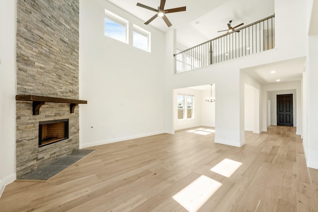1024 Emerald Trace Dr, Justin, TX 76247 - unfurnished living room with ceiling fan, a fireplace, wood finished floors, a towering ceiling, and baseboards