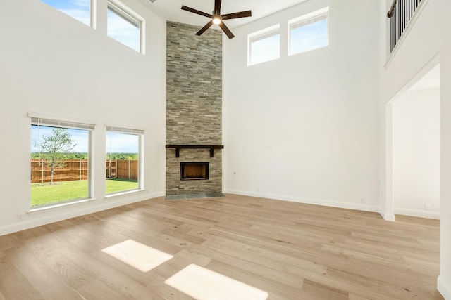 1024 Emerald Trace Dr, Justin, TX 76247 - unfurnished living room with a high ceiling, a ceiling fan, light wood finished floors, a fireplace, and baseboards