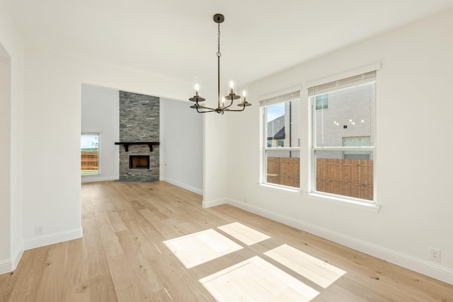 1024 Emerald Trace Dr, Justin, TX 76247 - unfurnished dining area featuring a chandelier, light wood-style floors, a fireplace, and baseboards