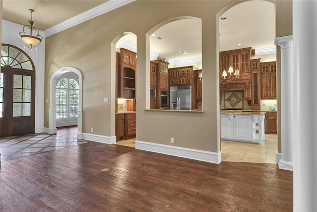 6805 Castle Pines Ct, Tyler, TX 75703 - unfurnished living room featuring ornamental molding, light wood finished floors, baseboards, arched walkways, and decorative columns