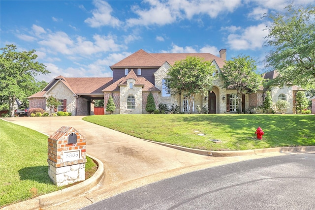 6805 Castle Pines Ct, Tyler, TX 75703 - french country style house with stone siding, concrete driveway, a chimney, a front yard, and brick siding