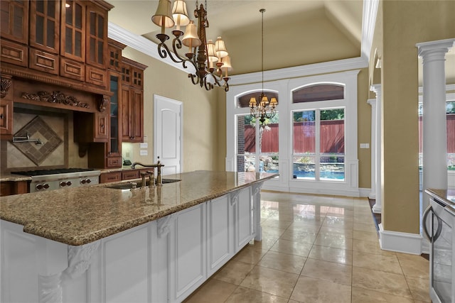6805 Castle Pines Ct, Tyler, TX 75703 - kitchen with a high ceiling, a chandelier, glass insert cabinets, a sink, and dark stone counters
