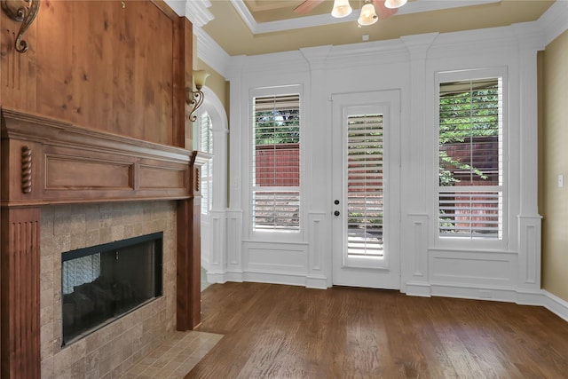 6805 Castle Pines Ct, Tyler, TX 75703 - doorway to outside featuring a decorative wall, dark wood-style flooring, a tile fireplace, a ceiling fan, and crown molding