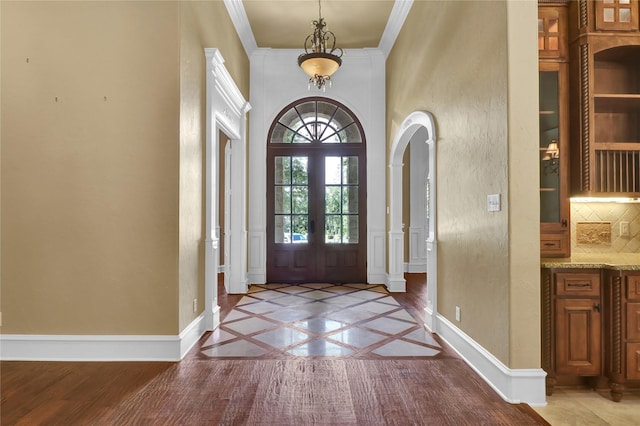 6805 Castle Pines Ct, Tyler, TX 75703 - entrance foyer with baseboards, inlaid floor details, french doors, crown molding, and arched walkways