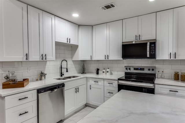 kitchen with stainless steel appliances, a sink, white cabinetry, tasteful backsplash, and recessed lighting