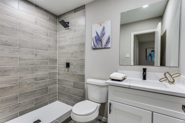 full bathroom featuring tiled shower, toilet, and vanity