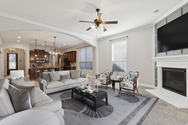 689 Barringer Ct, Fate, TX 75087 - living room featuring arched walkways, a chandelier, a glass covered fireplace, a ceiling fan, and baseboards