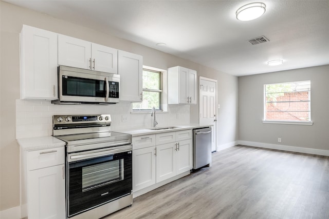324 Deer Creek Rd, Everman, TX 76140 - kitchen featuring appliances with stainless steel finishes, a sink, light countertops, backsplash, and light wood finished floors