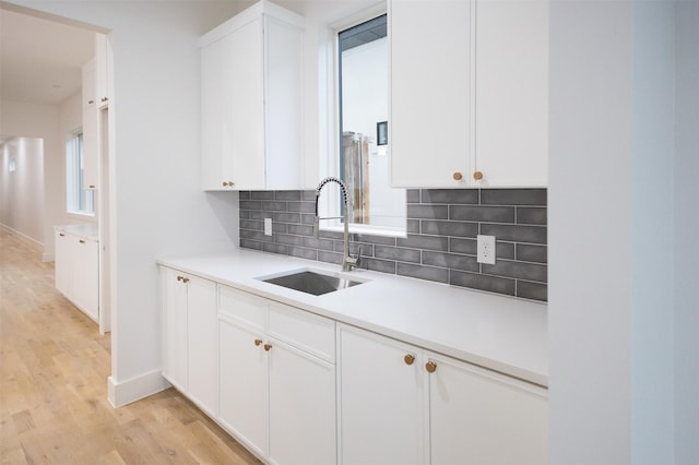 2935 Lovers Ln, University Park, TX 75225 - kitchen with a sink, decorative backsplash, light wood-type flooring, baseboards, and white cabinetry