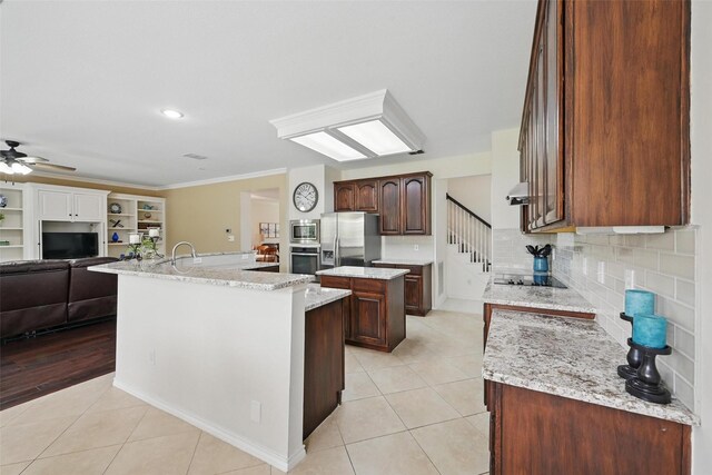 1500 Cool Springs Dr, Allen, TX 75013 - kitchen featuring a center island with sink, appliances with stainless steel finishes, light tile patterned floors, open floor plan, and crown molding