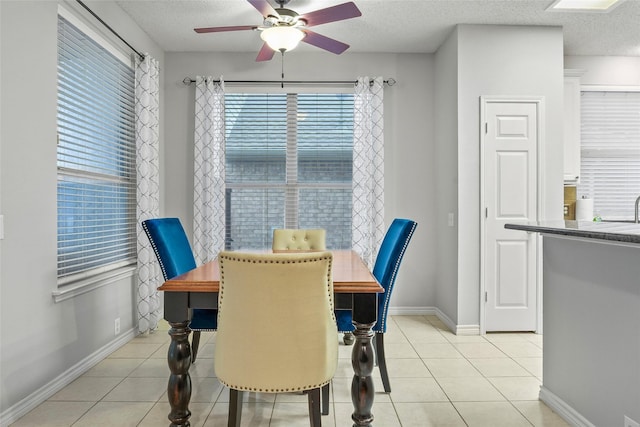 dining area with a ceiling fan, a textured ceiling, plenty of natural light, and light tile patterned floors