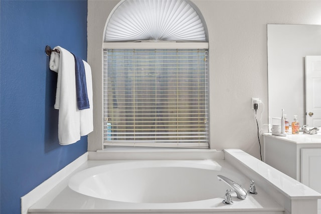 bathroom with a bath, vanity, and a textured wall