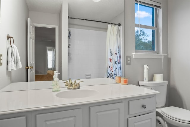 full bathroom featuring vanity, plenty of natural light, toilet, a shower with curtain, and a textured ceiling