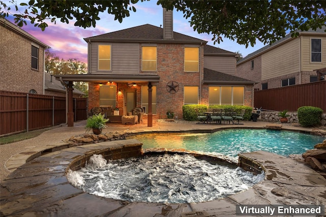 back of property at dusk featuring a chimney, brick siding, a patio, and a fenced backyard