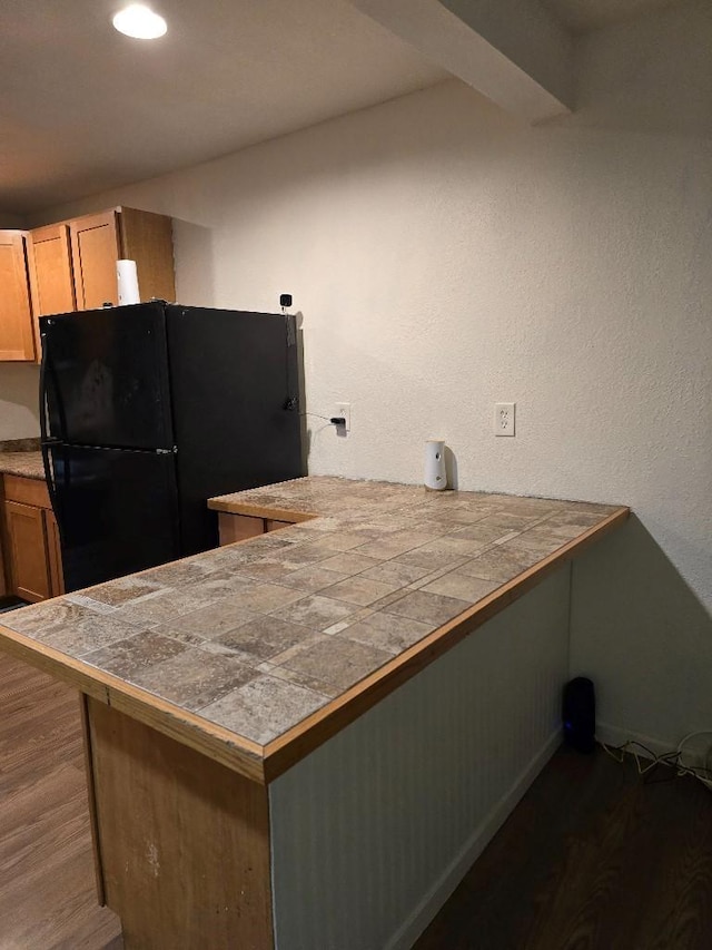 3915 Flory St, North Richland Hills, TX 76180 - kitchen with freestanding refrigerator, dark wood-style flooring, tile counters, a peninsula, and baseboards