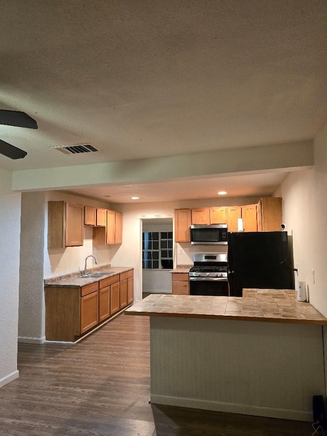 3915 Flory St, North Richland Hills, TX 76180 - kitchen featuring appliances with stainless steel finishes, a sink, a peninsula, dark wood-style floors, and baseboards