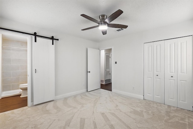 513 Edna Ct, Everman, TX 76140 - unfurnished bedroom featuring a closet, carpet floors, ensuite bathroom, a barn door, and baseboards